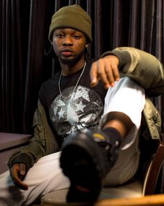 a young man sitting on top of a wooden chair