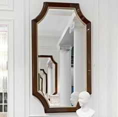 a mirror that is sitting on top of a mantle next to a busturine