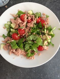 a white plate topped with meat and veggies next to a bottle of water