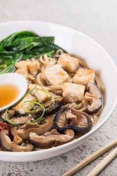 a white bowl filled with food next to chopsticks