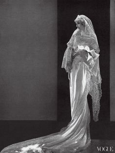 a black and white photo of a woman in a wedding dress with her veil pulled back