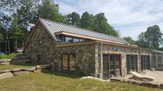 a stone building with a metal roof and windows on the outside, surrounded by grass