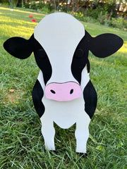 a black and white cow standing in the grass