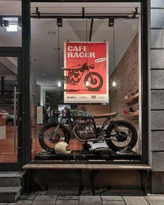 a motorcycle is displayed in the window of a cafe with an advertisement on the wall