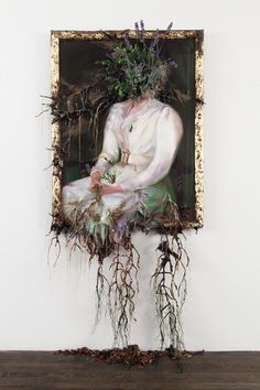 a painting hanging on the wall with plants growing out of it's head and body