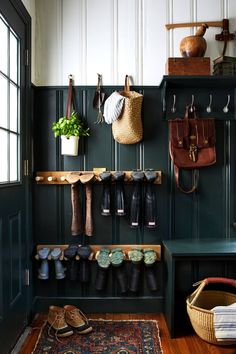 an entryway with green walls and wooden flooring filled with boots, hats, and purses