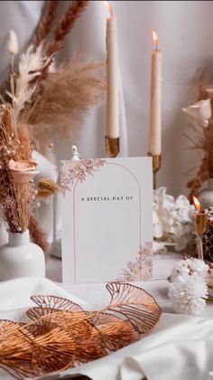 a table topped with candles and cards on top of a white cloth covered tablecloth