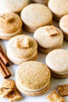 some cookies and cinnamon sticks are on a table with other food items around the edges