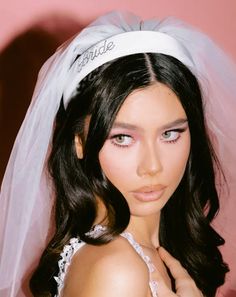 a woman in a wedding dress with a veil on her head and pink eyeshade