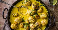 a pan filled with meatballs covered in sauce and garnished with parsley