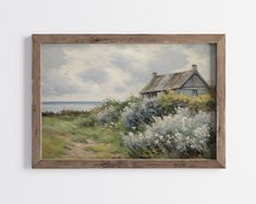 a painting hanging on the wall next to a white wall with a house and flowers