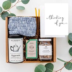 an open box containing tea, spices and greeting cards with the words thinking of you written on it