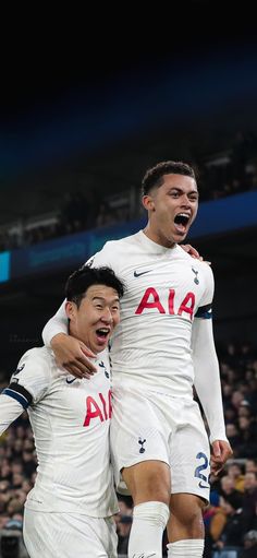 two soccer players are hugging each other in front of an audience at a sporting event