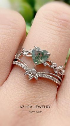 a woman's hand with two rings on top of her finger and an aqua green stone in the middle