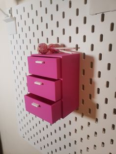 three pink drawers are on the wall in front of a white perfored background