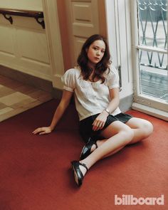 a woman sitting on the floor in front of a window