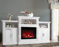 a white entertainment center with a fireplace and wine glasses on it's top shelf