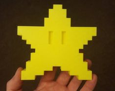 a hand holding a yellow piece of paper with an image of a star on it