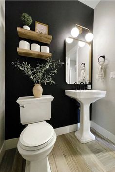 a white toilet sitting next to a sink in a bathroom under a mirror and lights