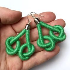 a pair of green earrings is being held in someone's hand with the word love written on it