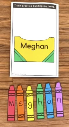 a wooden table with colorful crayons and the word meghan on it