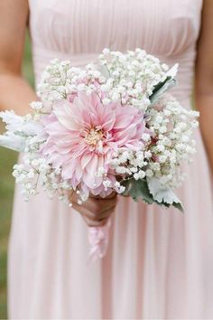 a bridesmaid holding a pink and white bouquet with baby's breath in it