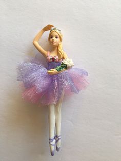 there is a doll that is wearing a purple dress and holding a flower in her hand