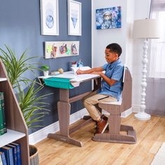 a young boy sitting at a desk writing on a piece of paper in his home office