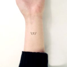 a woman's wrist with a small butterfly tattoo on the left side of her arm