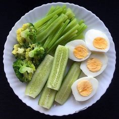 an egg, broccoli and hard boiled eggs on a white plate with black background