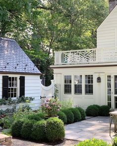 a white house surrounded by lush green trees and shrubbery in front of the house