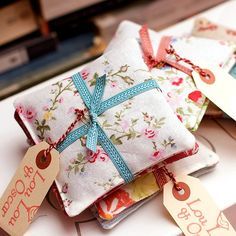 small gift bags with tags on them sitting on top of a white table next to books