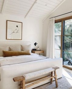 a bedroom with white walls and wooden furniture in front of a sliding glass door that leads to an outside deck