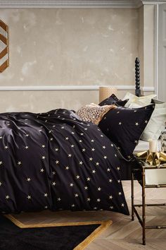 a bed with black and gold stars on the comforter, pillows and pillow cases