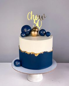 a blue and white cake with gold decorations on top that says chee 50 in the middle