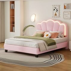 a bedroom with a pink bed and white rugs on the wooden floor, along with a large window