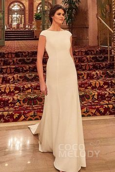 a woman in a white dress is standing on the floor next to some stairs and rugs