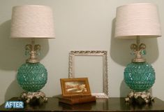 two lamps are sitting on a table next to a framed photograph and an empty frame