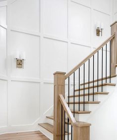 a staircase with white walls and wood handrails