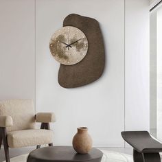 a large clock mounted to the side of a wall next to a chair and table