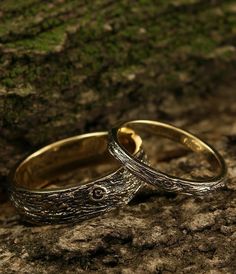 two wedding rings sitting on top of a rock