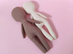 a small doll laying on top of a pink surface