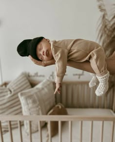 a baby sleeping in a crib with his hands on the side of it's head