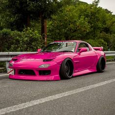 a pink sports car is parked on the road