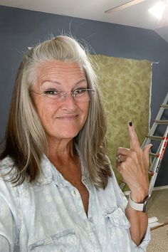 an older woman with glasses pointing at the camera