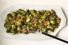 brussel sprouts on a white platter with spoons