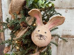 a stuffed bunny is hanging on a christmas wreath with lights and greenery around it