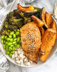 a white plate topped with chicken, broccoli and rice next to some sweet potatoes