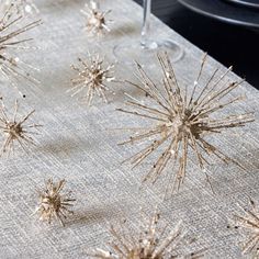 the table cloth is covered with small gold spiky stars and wine glasses on it