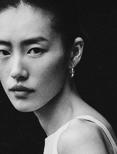 black and white photograph of a woman with earrings on her head looking at the camera